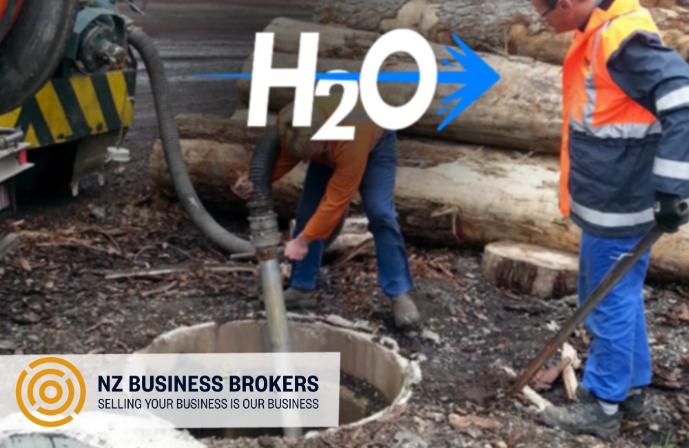 Two workers in hi-vis operating water infrastructure equipment on a job site