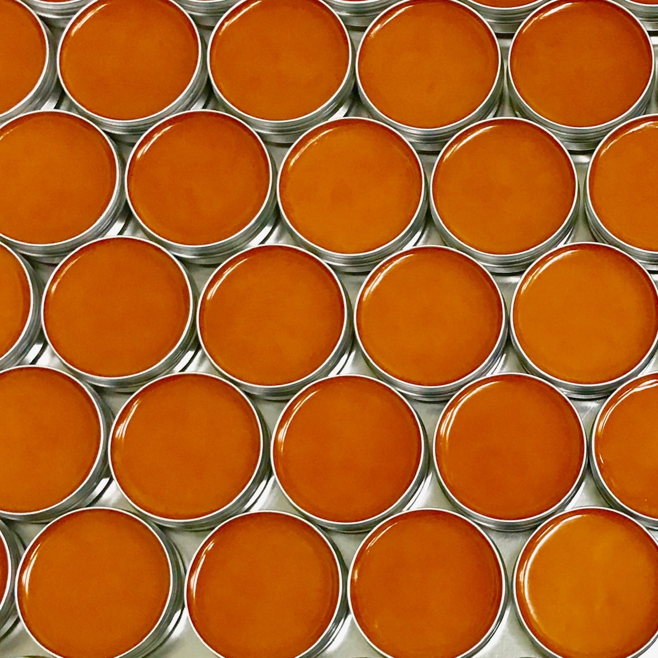 Rows of Omrub organic medical rub tins ready for distribution